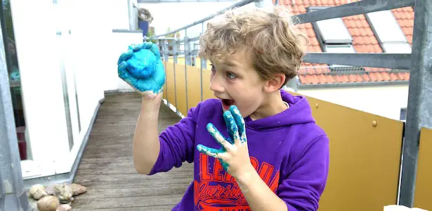 Kind beim Knete selber machen auf dem Balkon. Blaue Knete